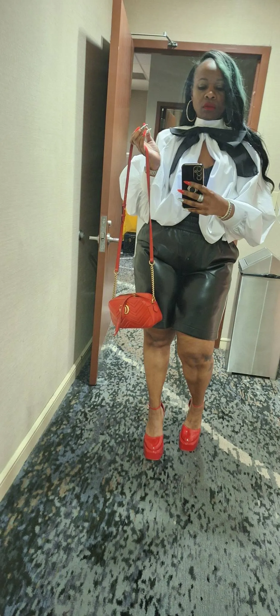 White blouse, black shorts, red heels, and red crossbody bag